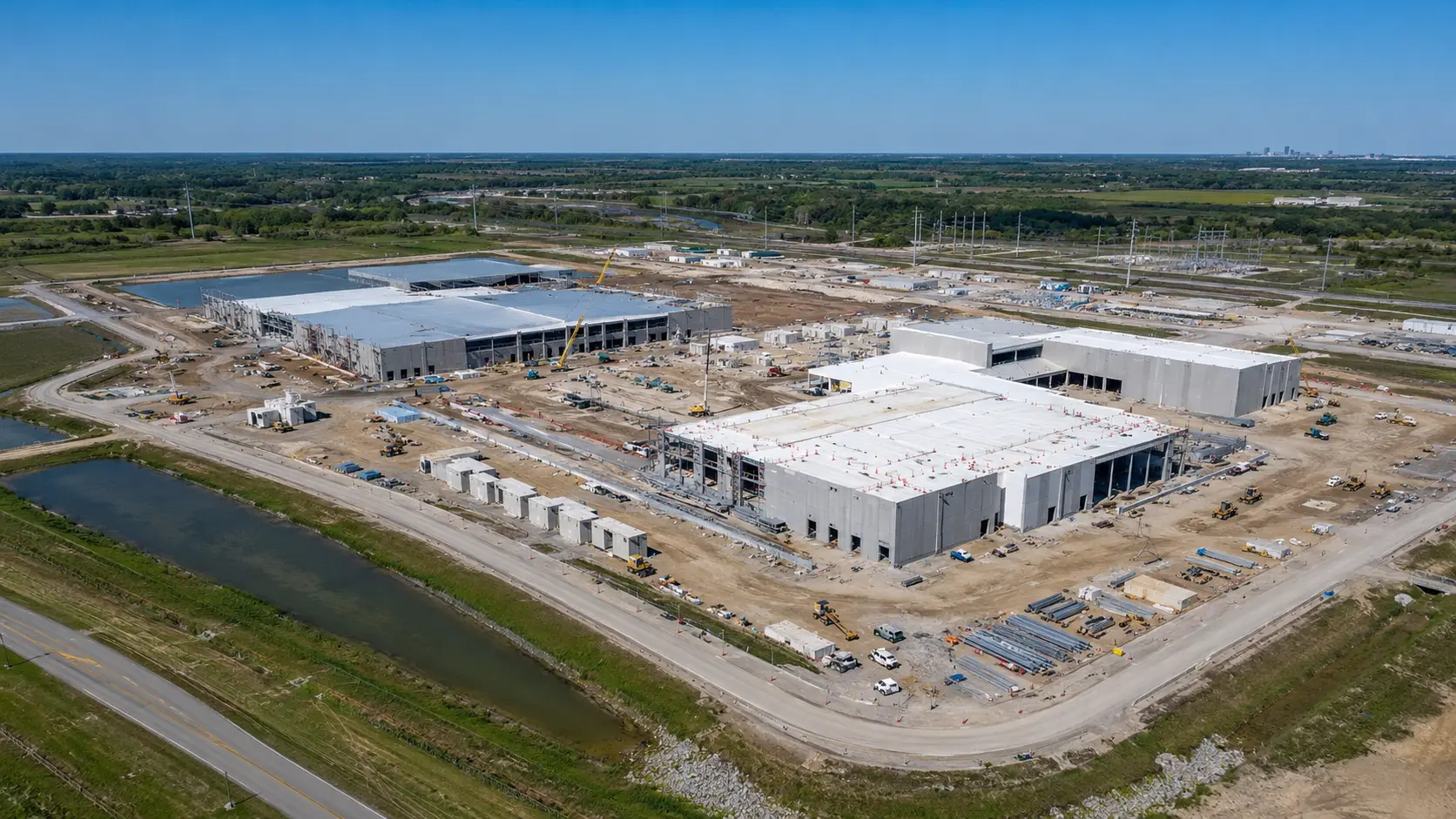Aerial view of a data center campus under construction, with shell buildings, cranes, and site work in progress